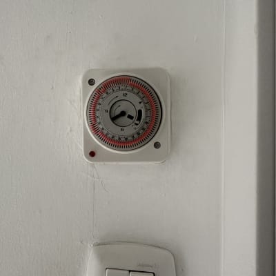 שעון טיימר חשמלי ומתגי תאורה על קיר