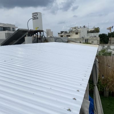 גג מתכת לבן עם צמחים וגדר במבוק