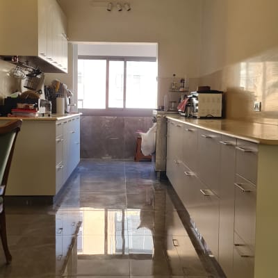 מטבח מודרני עם ארונות לבנים ומשטחי עבודה מבריקים