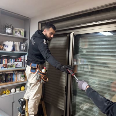 אדם על סולם מתקן תריסים עם מברג