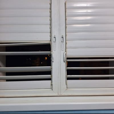 תריסים לבנים פתוחים למחצה עם ידיות מתכת