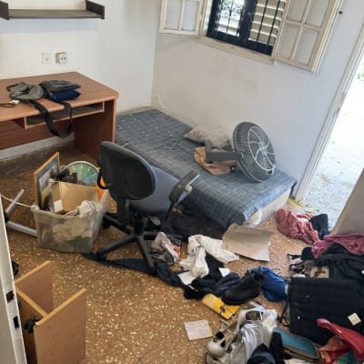 חדר מבולגן עם בגדים ופריטים מפוזרים על הרצפה