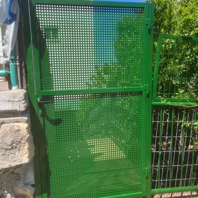 שער מתכת ירוק ליד בית ואדמה