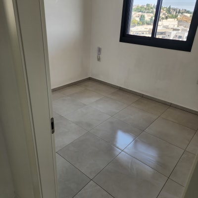 חדר ריק עם רצפת אריחים נקייה וחלון פתוח