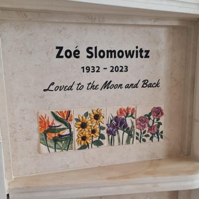 מצבה עם כיתוב ואריחי פרחים צבעוניים