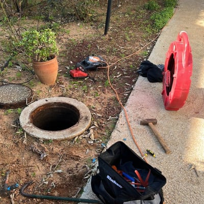 כלים ועבודות ליד פתח ביוב בגינה