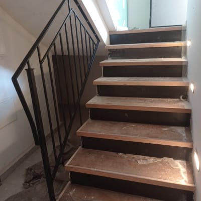 מעקה מתכת שחור ליד מדרגות עץ