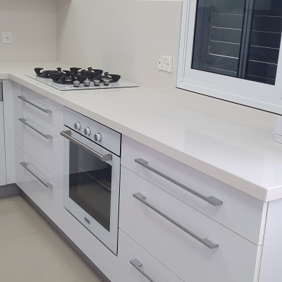 מטבח נקי עם משטח עבודה לבן וכיריים