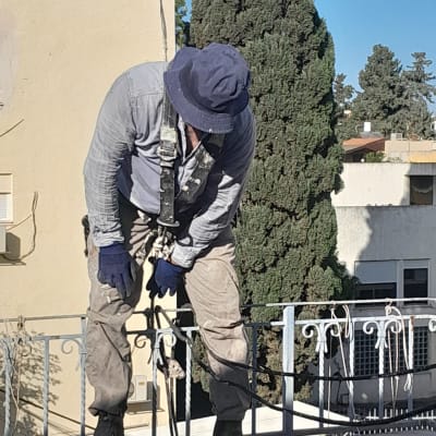 עובד בגובה המצויד ברתמת בטיחות מעל מעקה גג במהלך שיפוץ חזית
