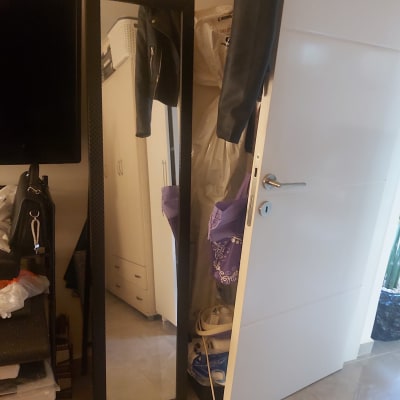 בגדים תלויים על דלת פתוחה עם מראה