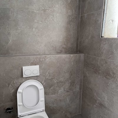 אסלה לבנה בחדר אמבטיה עם קירות אבן אפורים