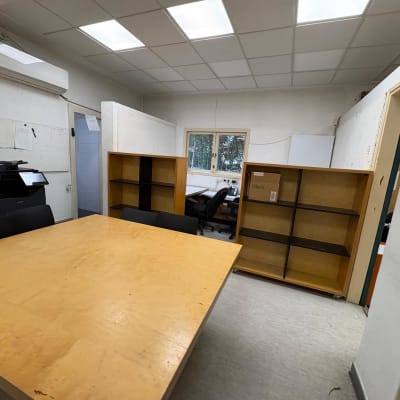 חדר עם שולחן עץ, מדפים וכיסאות, ללא אנשים