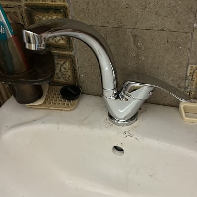 ברז כרום מותקן על כיור לבן עם ניקוז