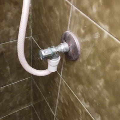 צינור מים מחובר לברז על קיר אריחים