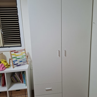 ארון לבן עם שתי דלתות ומדפים ליד חלון