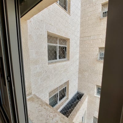 רשת יונים מותקנת על חלון בניין למניעת כניסת יונים