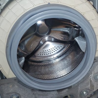 תוף מכונת כביסה פתוח עם חלקים פנימיים חשופים