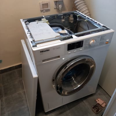 מכונת כביסה פתוחה עם כלים לתיקון חשמלי