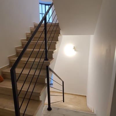 מעקה מתכת שחור במדרגות עץ בהירות