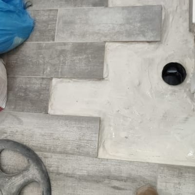 רצפה עם אריחים, חור ניקוז, רגל עם נעל עבודה