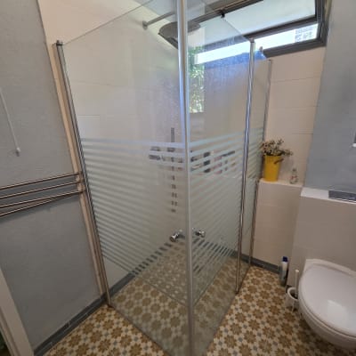 מקלחון זכוכית עם דלתות שקופות בחדר אמבטיה