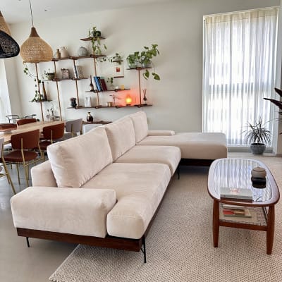 ספה בהירה ושולחן עץ בסלון מודרני עם מדפים וצמחים