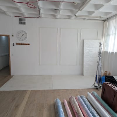 גלילי בד צבעוניים על רצפת עץ בחדר ריק עם קירות לבנים