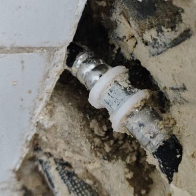 צינור מתכת עם חיבור פלסטיק בקיר חשוף