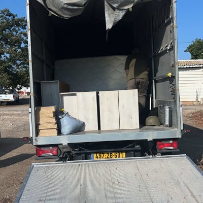 משאית פתוחה עם רהיטים וקרטונים בפנים