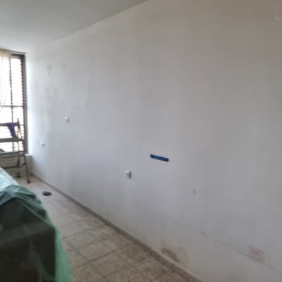 קיר צבוע חלקית עם רהיטים מכוסים בניילון