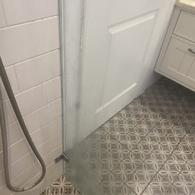 מקלחון עם דלת זכוכית ורצפת אריחים מעוצבת