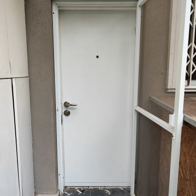 דלת לבנה עם ידית מתכת ומסגרת דלת חיצונית