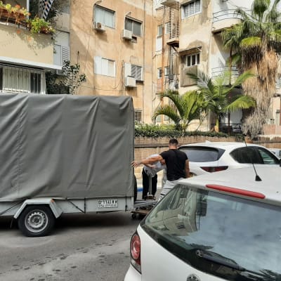 שני אנשים מעמיסים חפצים על עגלה מכוסה ברחוב