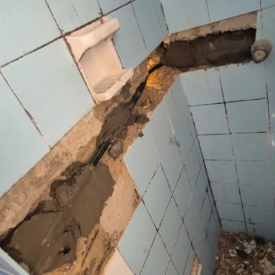 קיר אריחים שבור עם תיקון בטון וצינור חשוף