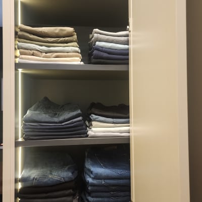 בגדים מקופלים בארון מואר עם מדפים