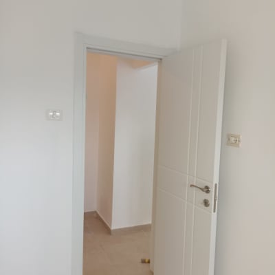 דלת פתוחה עם קיר לבן ורצפת אריחים