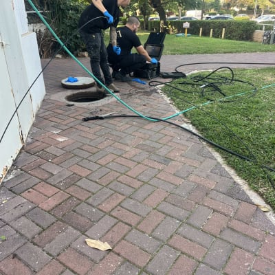 עובדים עם ציוד ליד פתח ביוב