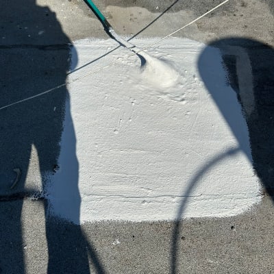מריחת חומר איטום לבן על משטח בטון