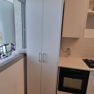 ארון מטבח עם ידיות מתכת ליד חלון