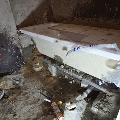 אמבטיה מותקנת עם צינורות וכלי עבודה על הרצפה