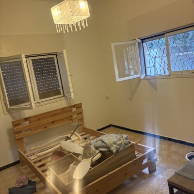 חדר ריק עם מיטה מפורקת וכלי ניקוי על הרצפה