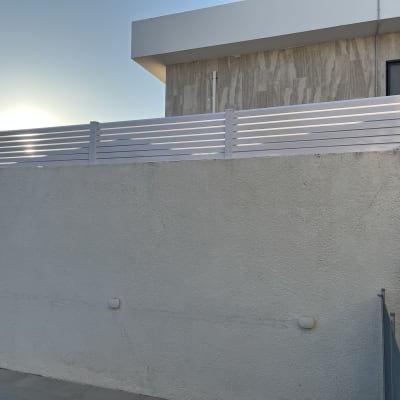 גדר אלומיניום לבנה על קיר בטון