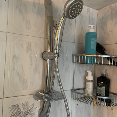 ראש מקלחת ומדף עם מוצרי טיפוח בחדר אמבטיה