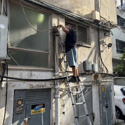 אדם על סולם מתקן צינור חיצוני בבניין