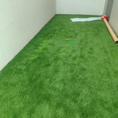 דשא סינתטי מותקן בחצר קטנה עם קיר במבוק