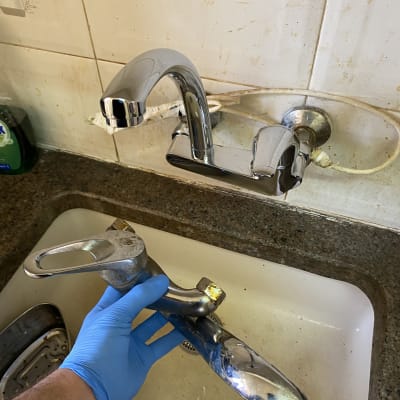 ברז כיור מוחזק ביד עם כפפה כחולה