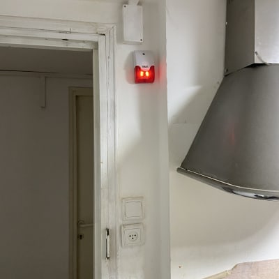 מכשיר אינטרקום עם נוריות אדומות על קיר לבן