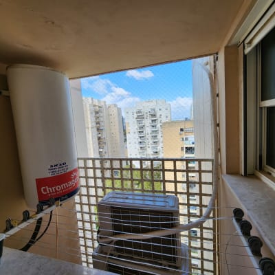 רשת יונים מותקנת במרפסת עם דוד שמש ומזגן