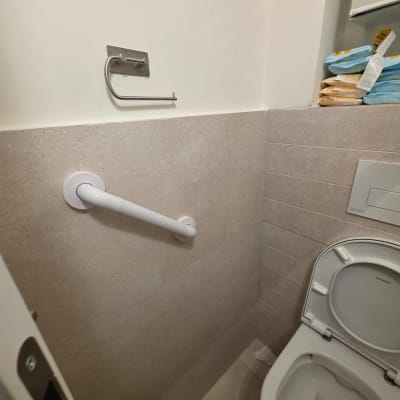 תמונה של חדר שירותים עם ידית אחיזה ומתקן לנייר טואלט