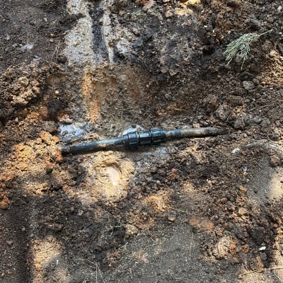 כלי עבודה וצינור מים באדמה רטובה